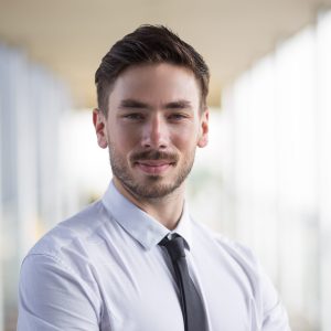 Portrait of optimistic businessman in formalwear confident in himself. Elegant man with beard looking at camera and standing in corridor. Entrepreneur concept